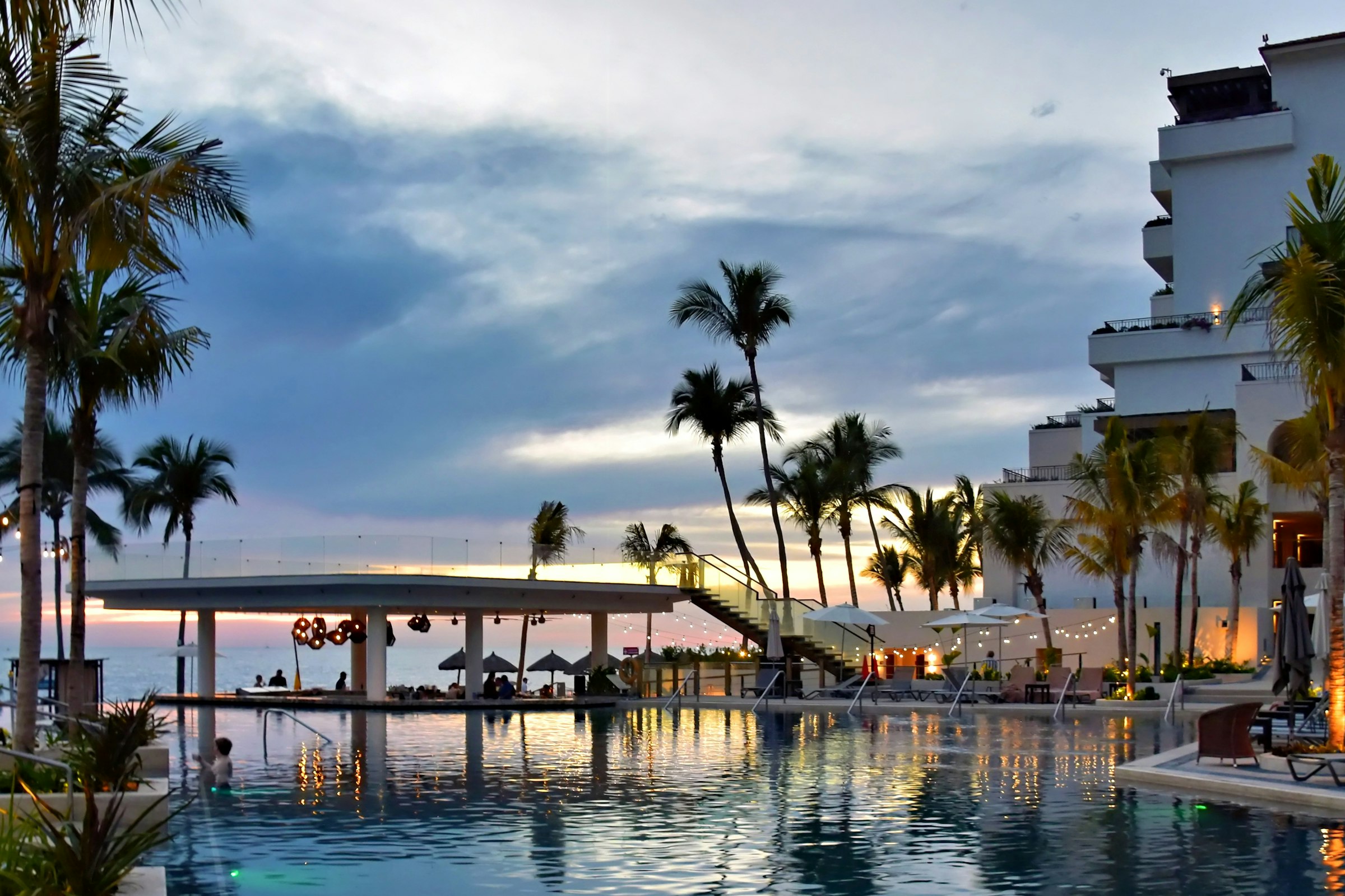 Guests enjoying a resort pool and terrace at sunset